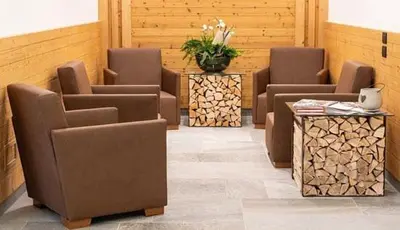 a waiting room with chairs and a table and flowers at Hotel Aurai in Osteria Alpina