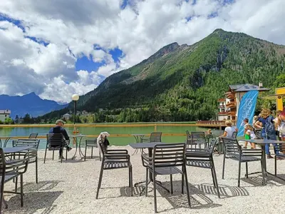 a group of people sitting at tables in front of a lake at Coldemies apartment in Alleghe