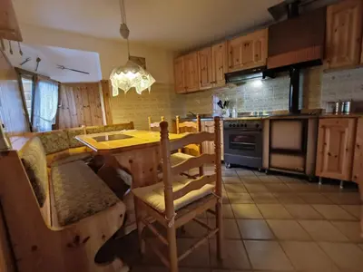 a kitchen with wooden cabinets and a table and chairs at Coldemies apartment in Alleghe