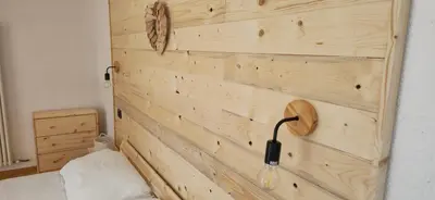 a bedroom with a wooden wall with a headboard at Rifugio di Niki in Falcade