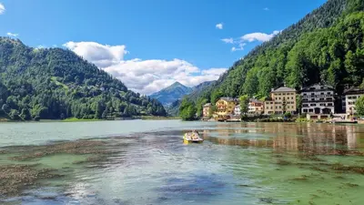 a small boat on a river in front of a village at Casa Cecilia Dolomiti - scenic views, pets welcome in Piaia