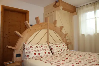 a bed with a wooden headboard in a bedroom at Agriturismo Pianrestel in Cavalese