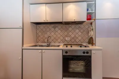 a kitchen with white cabinets and a sink and a stove at Casa Tamion in Vigo di Fassa