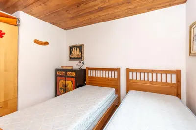 two beds in a room with wooden ceilings at Casa Tamion in Vigo di Fassa