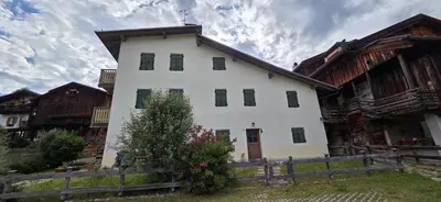a white house with a fence in front of it at Casa Tamion in Vigo di Fassa