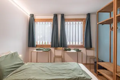 a bedroom with a bed and two tables and two windows at Ciasa Nü - Piano Rialzato in Pozza di Fassa