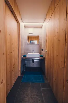 a bathroom with a sink and a mirror and wooden walls at Ciasa Nü - Piano Rialzato in Pozza di Fassa