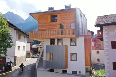 a wooden building with a balcony on a street at Ciasa Nü - Piano Rialzato in Pozza di Fassa