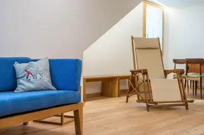 a living room with a blue couch and a chair at Ciasa Nü - Piano Rialzato in Pozza di Fassa