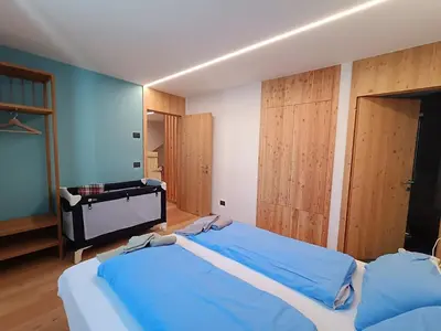 a bedroom with two blue beds and wooden doors at Ciasa Nü - Piano Rialzato in Pozza di Fassa