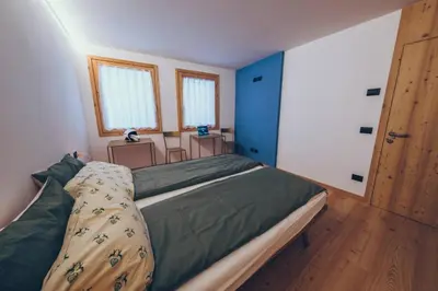 a bedroom with a large bed and two windows at Sella Ronda dalla Val di Fassa - CiasaNu 1° Piano in Pozza di Fassa