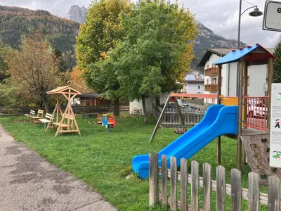 a yard with a playground with a slide and swings at Sella Ronda dalla Val di Fassa - CiasaNu 1° Piano in Pozza di Fassa
