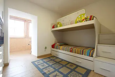 a childs bedroom with a bunk bed and a rug at Appartamento Diana in Cavalese
