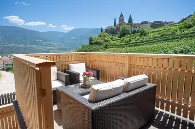 a patio with wicker chairs and a table with flowers at Ferienwohnung Zum Bachanger in Termeno
