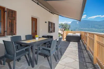 a patio with a table and chairs on a balcony at Ferienwohnung Zum Bachanger in Termeno