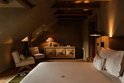 a bedroom with a white bed and a chair at Castel Badia - The Leading Hotels of the World in San Lorenzo di Sebato