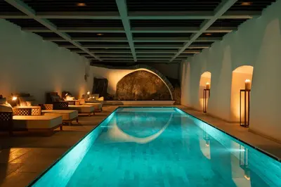 a swimming pool in a hotel with couches and chairs at Castel Badia - The Leading Hotels of the World in San Lorenzo di Sebato