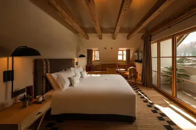 a bedroom with a large white bed and a table at Castel Badia - The Leading Hotels of the World in San Lorenzo di Sebato