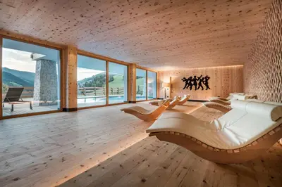 a bedroom with a large bed and large windows at Dependance Hotel Mareo Dolomites in San Vigilio Di Marebbe