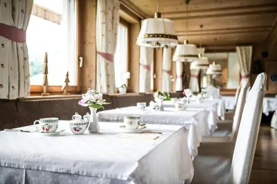a row of tables with white linens and flowers on them at Dependance Hotel Mareo Dolomites in San Vigilio Di Marebbe