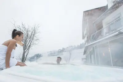 a man and a woman sitting in a tub of snow at Dependance Hotel Mareo Dolomites in San Vigilio Di Marebbe