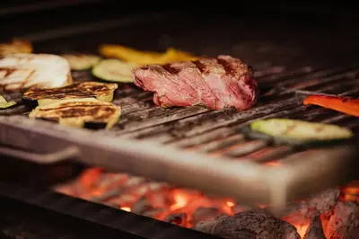 a steak and vegetables cooking on a grill at Dependance Hotel Mareo Dolomites in San Vigilio Di Marebbe