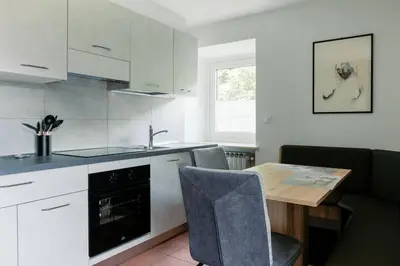 a kitchen with white cabinets and a table and a sink at Ciasa Silvano 1721 SV in Falcade