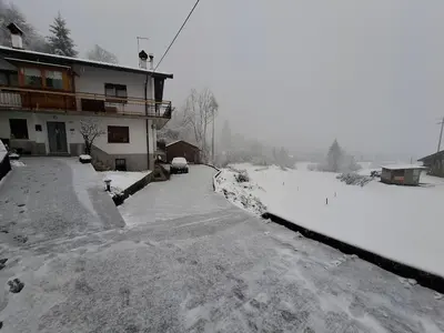 a snow covered street in front of a house at Appartamento Sot le Pale in Taibon
