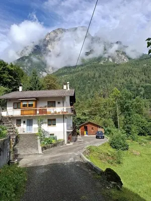 a house on the side of a road with a mountain at Appartamento Sot le Pale in Taibon