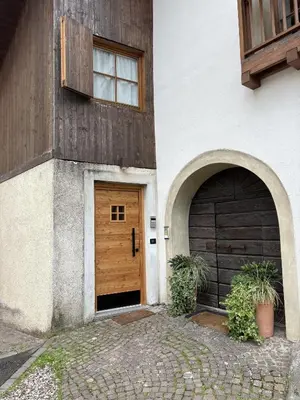 two entrances to a house with two garage doors at Fienile contemporaneo in Livo