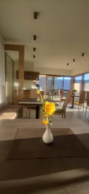 a living room with a vase with yellow flowers in it at Highlight Apartments in Appiano sulla Strada del Vino