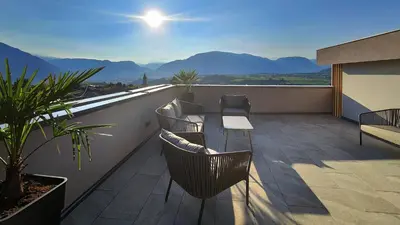 a balcony with chairs and a table and mountains at Highlight Apartments in Appiano sulla Strada del Vino