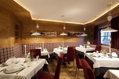 a dining room with white tables and red chairs at Hotel Christian in Corvara in Badia