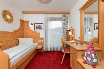 a hotel room with a bed and a desk and a mirror at Hotel Christian in Corvara in Badia