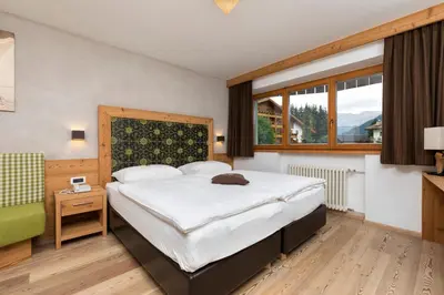 a bedroom with a large bed and a large window at Hotel Christian in Corvara in Badia