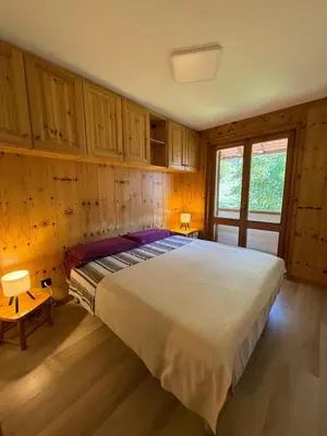 a bedroom with a large bed with wooden cabinets at Appartamento DOLOMITES con BOX privato in Canazei