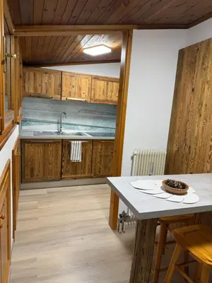 a kitchen with wooden cabinets and a table at Appartamento DOLOMITES con BOX privato in Canazei