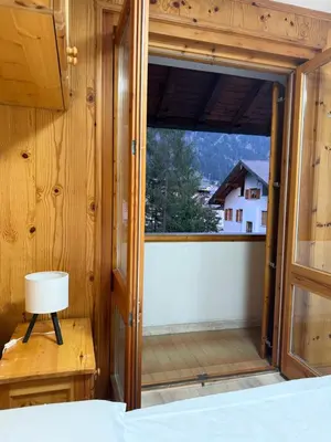 a bedroom with a door open to a balcony at Appartamento DOLOMITES con BOX privato in Canazei