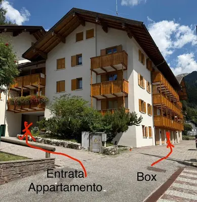 a building with a red ribbon in front of it at Appartamento DOLOMITES con BOX privato in Canazei