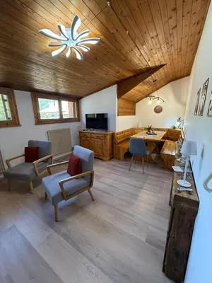 a living room with a wooden ceiling and a table at Appartamento DOLOMITES con BOX privato in Canazei
