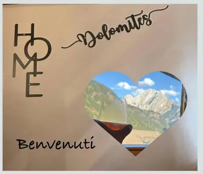 a glass of wine next to a picture of a heart at Appartamento DOLOMITES con BOX privato in Canazei