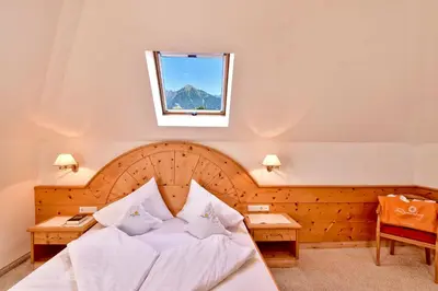 a bedroom with a bed with white sheets and a window at Hotel Sonnenburg in Merano