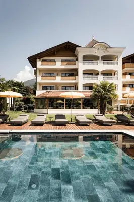 a hotel with a swimming pool in front of a building at Hotel Sonnenburg in Merano