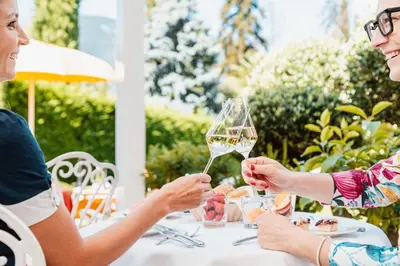 two women sitting at a table with a glass of wine at Hotel Sonnenburg in Merano