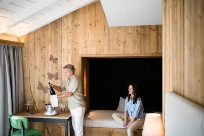 a woman sitting on a bed with a plate of food at Mirabell Dolomites Hotel in Valdaora