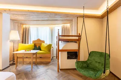 a bedroom with a large bed and a desk at Mirabell Dolomites Hotel in Valdaora