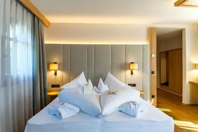 a hotel room with two beds and a flat screen tv at Mirabell Dolomites Hotel in Valdaora