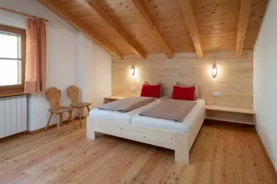 a bedroom with a bed with red pillows on it at Thalerhof in Feldthurns