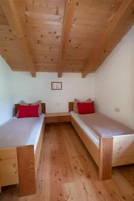 two beds in a room with wooden ceilings at Thalerhof in Feldthurns