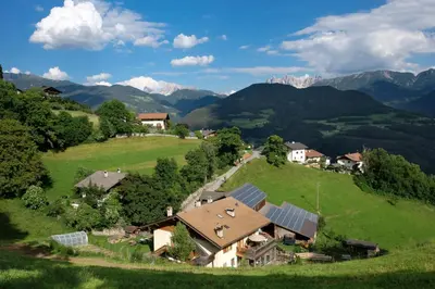 an aerial view of a house on a hill with mountains at Thalerhof in Feldthurns